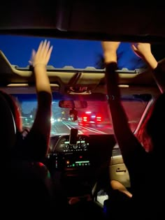 two people in a car with their hands on the steering wheel while driving at night