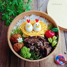 a bowl filled with rice, meat and veggies on top of a wooden table