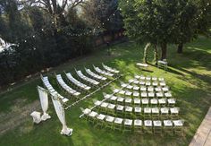 an outdoor ceremony set up with white chairs