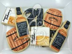 decorated cookies in the shape of wine bottles and barrels on a white plate with black writing