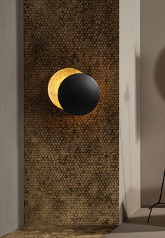 a black and yellow wall light on the side of a wall next to a chair