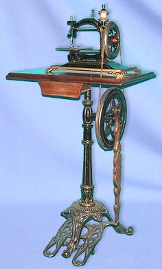 an antique sewing machine on a stand with blue background and white backdrop in the back ground