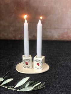 two white candles sitting on top of a plate