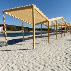 a row of wooden benches sitting on top of a sandy beach