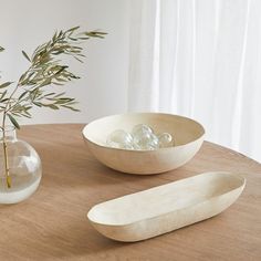 a wooden table topped with two bowls and a vase filled with rocks on top of it