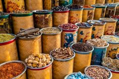 many buckets filled with different types of food and spices on display in front of each other