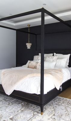 a four poster bed with white sheets and pillows