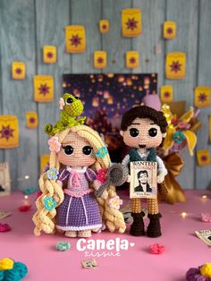 two little dolls are standing next to each other in front of a cake with decorations on it