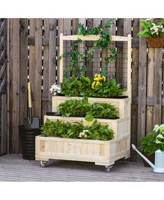 three wooden boxes filled with plants on top of a wooden floor next to a fence