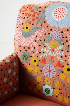 an upholstered orange chair with colorful flowers and polka dots on the backrest