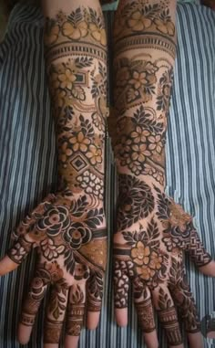 two hands with henna tattoos on them, one is showing off the intricate design