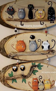 three wooden spoons with cats painted on them are hanging from the wall in front of each other