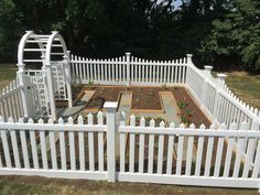 a white picket fence surrounding a vegetable garden