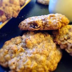 three oatmeal cookies stacked on top of each other with an apple in the background