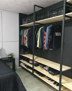 an organized closet with clothes and shoes on the shelves, along with a bed in the foreground