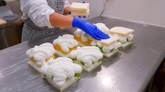 a person in blue gloves is decorating small food items on a silver counter top