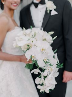 the bride and groom are posing for a photo with white flowers in their bouquets