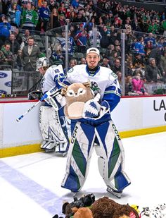 a hockey player holding stuffed animals on the ice