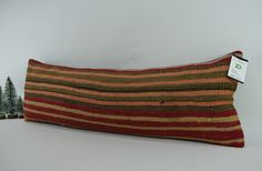 a decorative striped pillow sitting on top of a white table next to two small trees