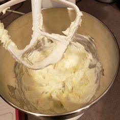 a metal bowl filled with white frosting on top of a counter