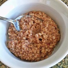 a bowl filled with oatmeal sitting on top of a counter next to a spoon