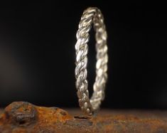 two silver rings sitting on top of a rusted piece of metal in front of a black background