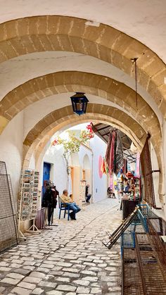 people are sitting on benches under an archway