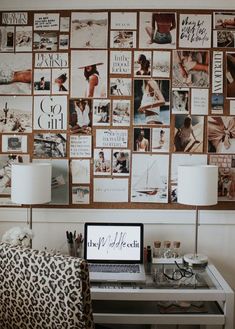 a laptop computer sitting on top of a desk in front of a wall covered with pictures