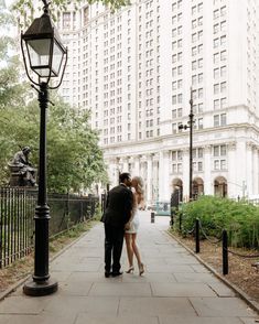 a man and woman standing next to each other under a street light on a sidewalk