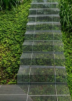 three metal cages are stacked on top of each other in front of green bushes and shrubbery