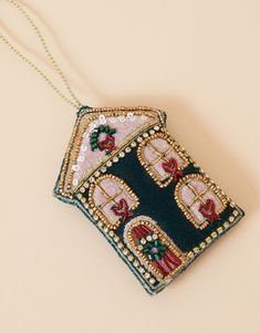 an embroidered ornament hanging from a chain on a table with a white background