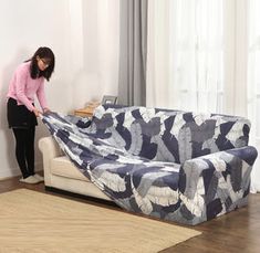 a woman standing next to a couch covered in a blue and white blanket with the words elastic sofa cover 50 + colors