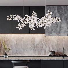 a modern kitchen with marble counter tops and black cabinets, white flowers hanging from the ceiling