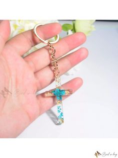 a hand holding a cross shaped key chain