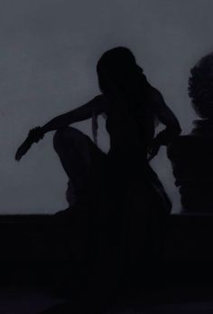 the silhouette of a woman in a long dress sitting on a ledge with her hands behind her back