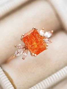 an orange diamond ring sitting on top of a white box