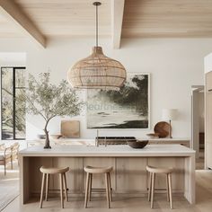 a kitchen island with three stools in front of it and a painting on the wall