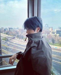 a man with blue hair looking out the window