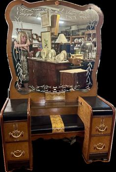 an antique vanity with mirror and stool in front of it, showing the woman's reflection