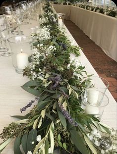 a long table with candles and greenery on the top is set up for a formal function