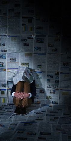 a person sitting on the floor covered in newspapers