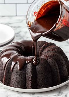 someone pouring chocolate sauce on top of a bundt cake