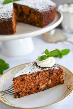 a piece of cake on a plate with a fork in front of it and mint sprig