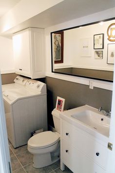 a white toilet sitting next to a sink in a bathroom under a mirror above a washer and dryer