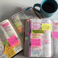 an open book with sticky notes on it next to a cup of coffee