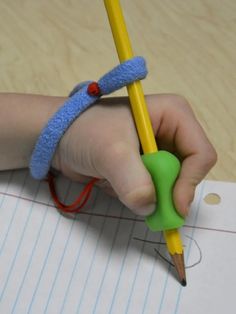 a child's hand holding a pencil and writing on lined paper