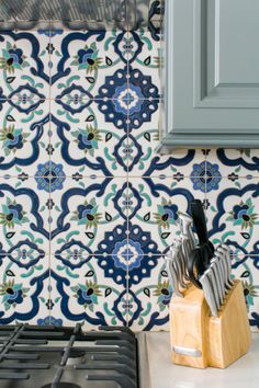 a stove top oven sitting next to a blue and white wall with tile on it