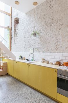 a kitchen with yellow cabinets and an open staircase leading up to the second floor area