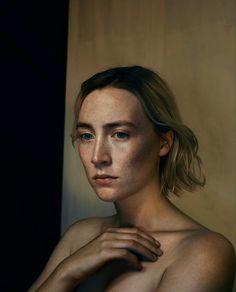 a woman with freckled hair and blue eyes poses for a photo in front of a wall