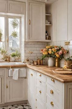 a kitchen filled with lots of white cabinets and counter top next to a window covered in flowers